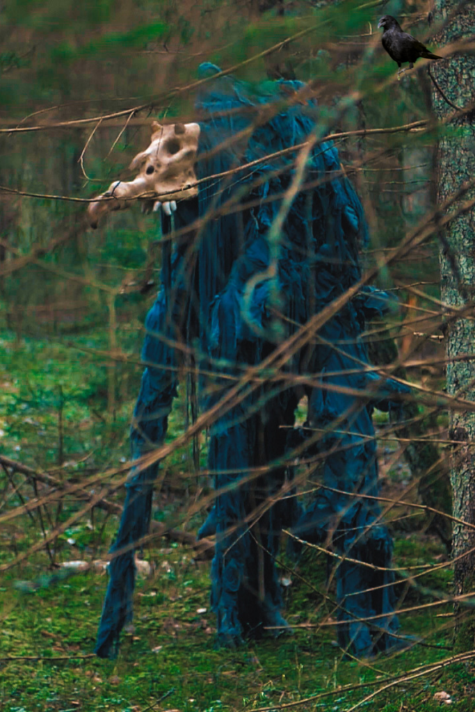 A creature with a skull head walks in the woods.